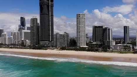 Surfers-Paradise,-Queensland-Australia---February-28-2021:-Aerial-moving-forward-over-the-Pacific-Ocean-to-the-beach-and-high-rise-buildings-of-the-Gold-Coast
