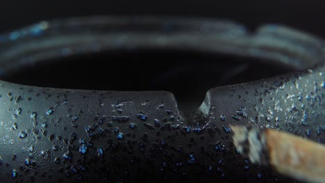 A-macro-close-up-shot-of-ash-residue-from-a-cigarette-in-a-black-stone-ashtray,-slow-motion-4K-video,-white-smoke