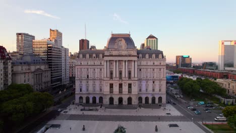 Aerial-view-dolly-in-front-of-the-Kirchner-Cultural-Center-at-sunset-in-the-background,-downtown-Buenos-Aires