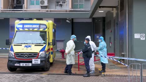 A-police-officer,-health-workers,-and-an-ambulance-vehicle-are-seen-outside-a-building-placed-under-lockdown-at-a-public-housing-complex-after-a-large-number-of-residents-tested-positive-in-Hong-Kong