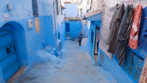 Male-Walking-Down-Local-Street-Steps-In-Chefchaouen-In-Morocco