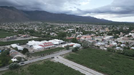 Aerial-Drone-Above-Cafayate-Vineyards-and-Town,-Scenic-Grape-Production-Field-and-Agricultural-Village-next-to-Andean-Cordillera,-Salta,-Argentina