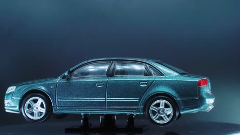 Ein-Winziges-Modellauto-Aus-Metall-Auf-Einem-Drehbaren-Ständer-Mit-Studiobeleuchtung,-Nahaufnahme,-4k-Video,-Silbernen-Rädern,-Schwarzen-Reifen,-Türen-Und-Fenstern