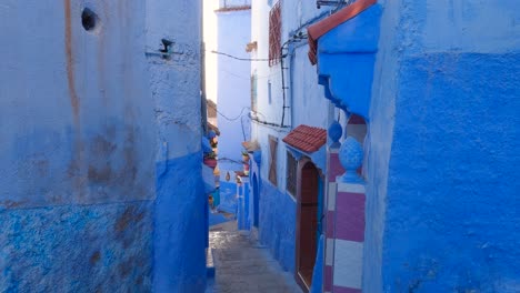 Quaint-steep-alley-with-blue-painted-walls-in-touristic-Chefchaouen,-Morocco