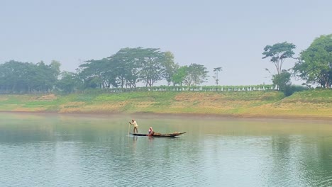 Wide-view-of-fisherman-with-woman-navigating-on-traditional-Asian-fishing-boat