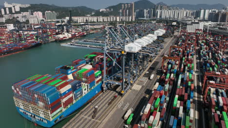 Luftaufnahme-Eines-Krans,-Der-An-Einem-Sonnigen-Tag-Ein-Riesiges-Containerschiff-Im-Hafen-Von-Hongkong-Belädt