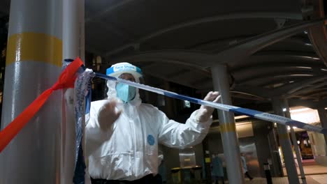 An-officer-sets-up-a-police-cordon-tape-as-he-wears-a-protective-suit-while-a-building-is-under-lockdown-after-a-large-number-of-residents-tested-Covid-19-Coronavirus-positive