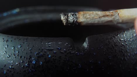 A-macro-close-up-shot-of-ash-residue-from-a-cigarette-in-a-black-stone-ashtray,-slow-motion-4K-video,-white-smoke-2