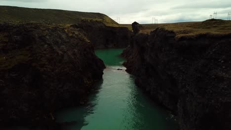 Aerial-drone-view-over-river-water-flowing-through-a-gorge,-in-Iceland