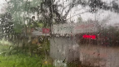 Raindrops-rolling-down-window-of-vehicle-while-travelling-road