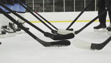 Competencia-De-Hockey-Sobre-Hielo,-Los-Jugadores-Están-Poniendo-Sus-Palos-De-Hockey-En-Una-Fila-Y-Golpeando-Suavemente-El-Hielo-Con-Ellos