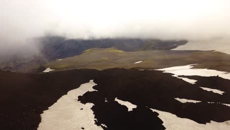 Aerial-landscape-view-of-mountains-with-melting-snow,-on-a-cloudy-and-foggy-day,-Fimmvörðuháls-area,-Iceland