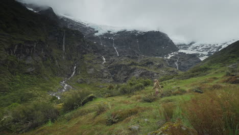 Mujer-Caminando-Por-El-Verde-Valle-Alpino-Con-Espectaculares-Montañas-Altas