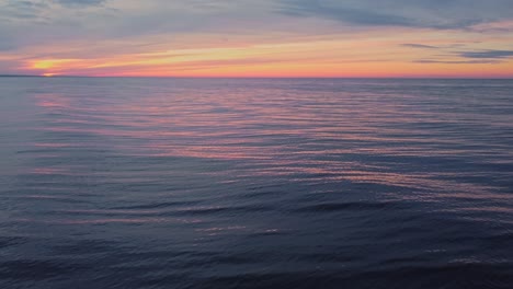 Calm-sea-water-surface-and-orange-sunset-or-sunrise-sky,-static-view