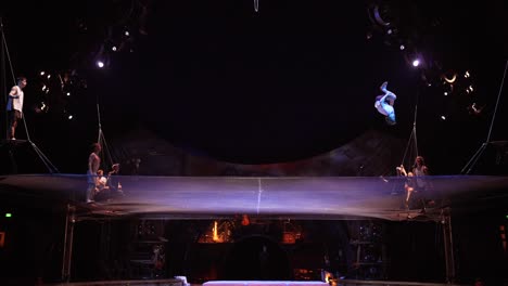 Cirque-Du-Soleil:-Atletas-De-Circo-Profesionales-Practicando-Y-Ensayando-El-Acto-De-Trampolín-En-Un-Impresionante-Lugar-Con-Luz-Tenue