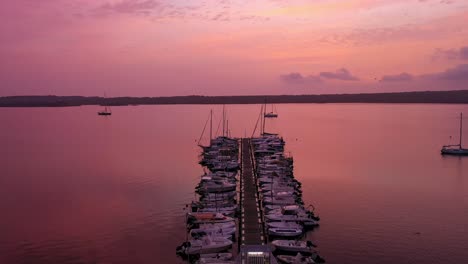 Aerial-View-of-boats-on-a-dock-with-a-beautiful-sunset,-tracking-wide-shot