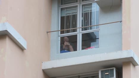 A-woman-uses-her-smartphone-to-film-out-of-her-apartment's-window-as-the-residential-building-is-under-forced-lockdown-after-a-large-number-of-residents-tested-positive