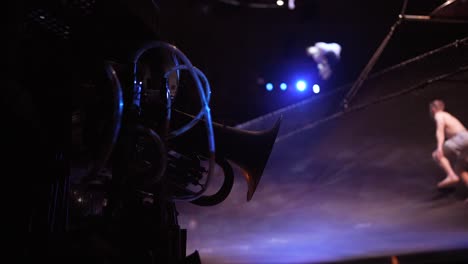 Cirque-Du-Soleil:-Professionelle-Zirkusathleten-üben-Und-Proben-Trampolin-Darbietungen-In-Einem-Atemberaubenden-Ort-Mit-Gedämpftem-Licht,-Statue-Im-Vordergrund
