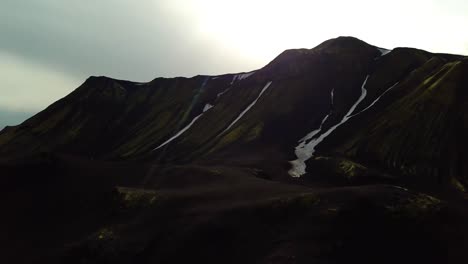 Luftlandschaftsansicht-Der-Dunklen-Berge-Des-Isländischen-Hochlandes,-Mit-Kleinen-Flecken-Von-Schmelzendem-Schnee,-An-Einem-Bewölkten-Tag