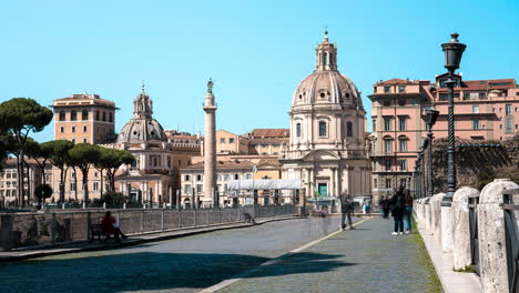 Time-lapse-of-pedestrians-walking-through-the-city-streets-of-Rome-with-the-Catholic-church,-Chiesa-del-Santissimo-Nome-di-Maria-al-Foro-Traiano,-standing-prominently-in-the-background
