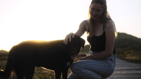 Young-woman-interacts-friendly-with-her-dog-while-sunset