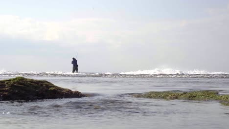 Strand-Mit-Rauer-See-Und-Vielen-Wellen,-Mit-Einem-Fischer-Im-Hintergrund