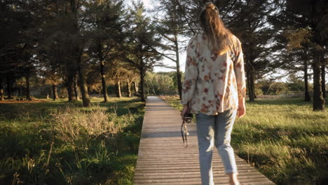 Mujer-Joven-Y-Su-Perro-Caminando-En-Un-Paseo-Marítimo-En-Un-Parque-Nacional-Mientras-Se-Pone-El-Sol