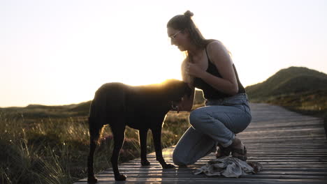 Zeitlupenvideo-Einer-Jungen-Hündin-Und-Ihres-Hundes,-Die-Bei-Sonnenuntergang-Liebevoll-Miteinander-Interagieren