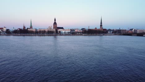 Aerial-opening-shot-of-Latvian-capital-city-Riga,-dolly-in-over-river-Daugava