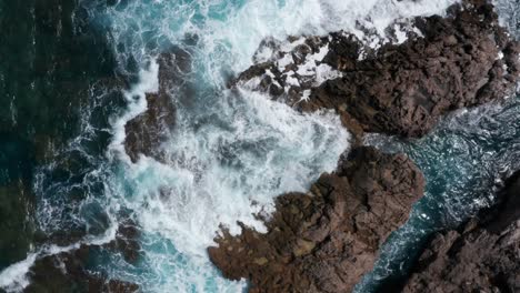 Waves-crashing-onto-rocky-shoreline-on-island-of-Mallorca-with-blue-water