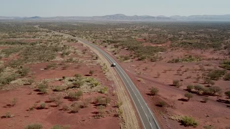 Aufsteigende-Luftaufnahme-Eines-Einsamen-Autos,-Das-In-Der-Hitze-Des-Tages-Durch-Australiens-Karijini-Nationalpark-Fährt