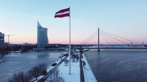 Patriotic-Latvian-flag-raised-on-flag-pole-in-winter,-celebrating-national-independence-day