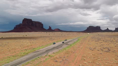 Drone-shot-of-vehicles-passing-in-a-road-at-the-middle-of-the-desert