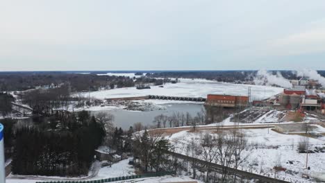 Aerial,-Stevens-Point-water-tower-during-winter-season,-frozen-Wisconsin-river