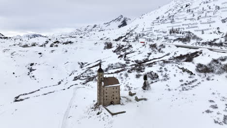 Old-Spittel-hospiz-at-the-black-asphalt-road-over-the-with-snow-covered-Simplon-pass-on-a-cloudy-day