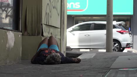 Handheld-shot-of-Malaysian-drug-addict-lying-down-on-the-street-during-daytime