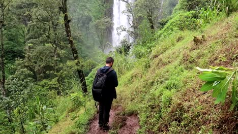 Young-backpacker-man-checking-the-flight-of-a-drone-in-Materuni-Waterfall