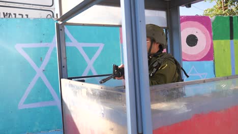 Armed-IDF-soldier-in-cabin-in-security-checkpoint,-arch-shot