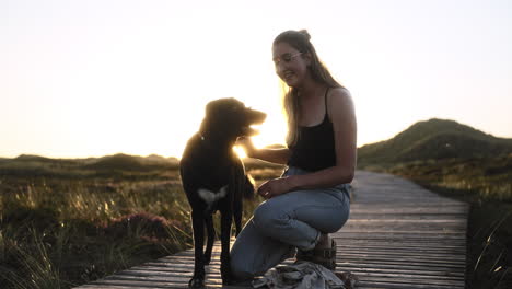 Slow-motion-of-a-young-woman-and-her-dog-while-sunset