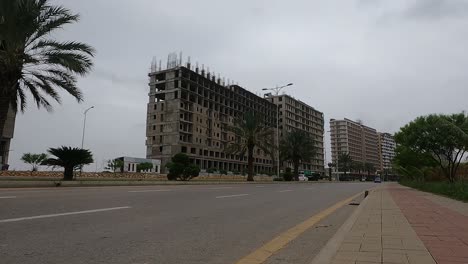 Vista-De-ángulo-Bajo-A-Lo-Largo-De-La-Carretera-Con-El-Tráfico-Pasando-Junto-A-Los-Desarrollos-En-El-Desarrollo-De-Viviendas-De-Bahria-En-Karachi