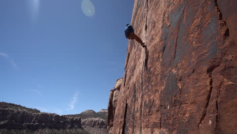 Climber-Going-Down-on-Vertical-Climbing-Rock-Using-Ropes,-Low-Angle-60fps