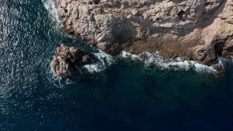 Drone-shot-waves-crashing-onto-shoreline-with-seagull-passing-through-the-shot