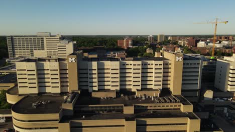 University-of-Michigan-hospital-building-complex,-aerial-fly-away-view-during-sunset