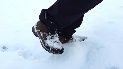 Medium-close-up-of-male-hiker-walking-through-powdery-snow-up-a-hill