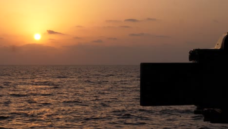 Silhouette-Of-Flip-Out-Screen-Of-Camera-Filming-Orange-Sunset-Over-Ocean
