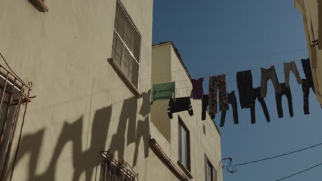 low-angle-panning-shot-of-clothes-hanging-on-a-wire-outside-to-dry-int-he-California-sun