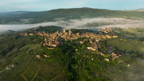 Vista-Panorámica-Sobre-La-Ciudad-De-San-Gimignano-Con-Niebla-Sobre-Las-Colinas-En-Toscana,-Italia---Toma-Aérea-De-Drones