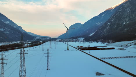 Lange-Stromleitungen-Neben-Einer-Modernen-Rotierenden-Windmühle-Im-Rhonetal-An-Einem-Winterabend