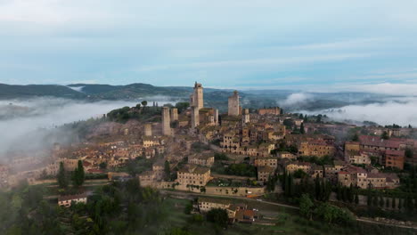 Vista-Panorámica-Sobre-El-Paisaje-Brumoso-En-San-Gimignano,-Toscana,-Italia---Toma-Aérea-De-Drones
