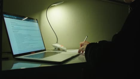 Eine-Person-Macht-Sich-Notizen-Auf-Einem-Laptop,-Während-Sie-In-Einer-Büroumgebung-Arbeitet